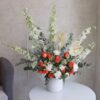 A vase containing delphiniums, anthuriums, roses and carnations by Novo